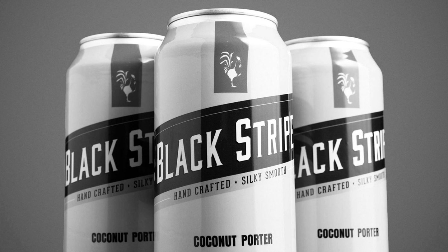 A black and white photo of three Black Stripe, Coconut Porter cans