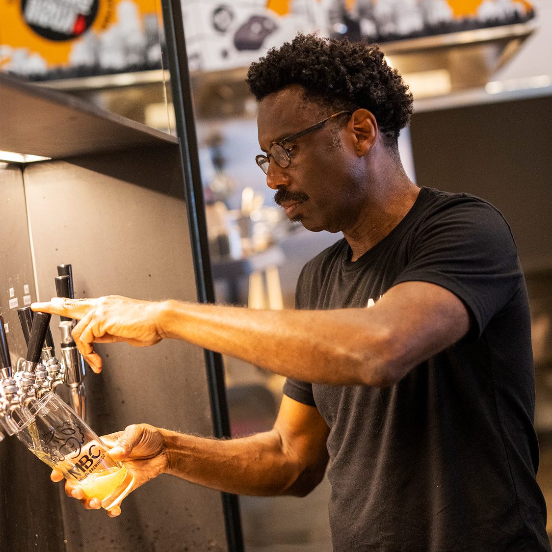 Rodney Hines, CEO, using the beer tap to fill an MBC glass.
